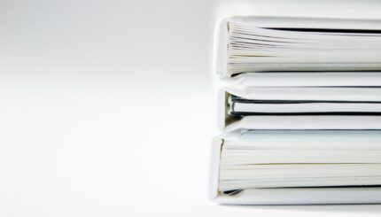 A stack of thick folders on a white surface