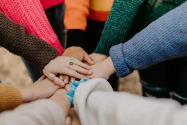 GROUPE DE PERSONNES POSANT LEURS MAINS LES UNES SUR LES AUTRES