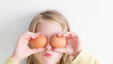 PETITE FILLE AVEC DES OEUFS DE PULE DANS LES MAINS DEVANT LES YEUX